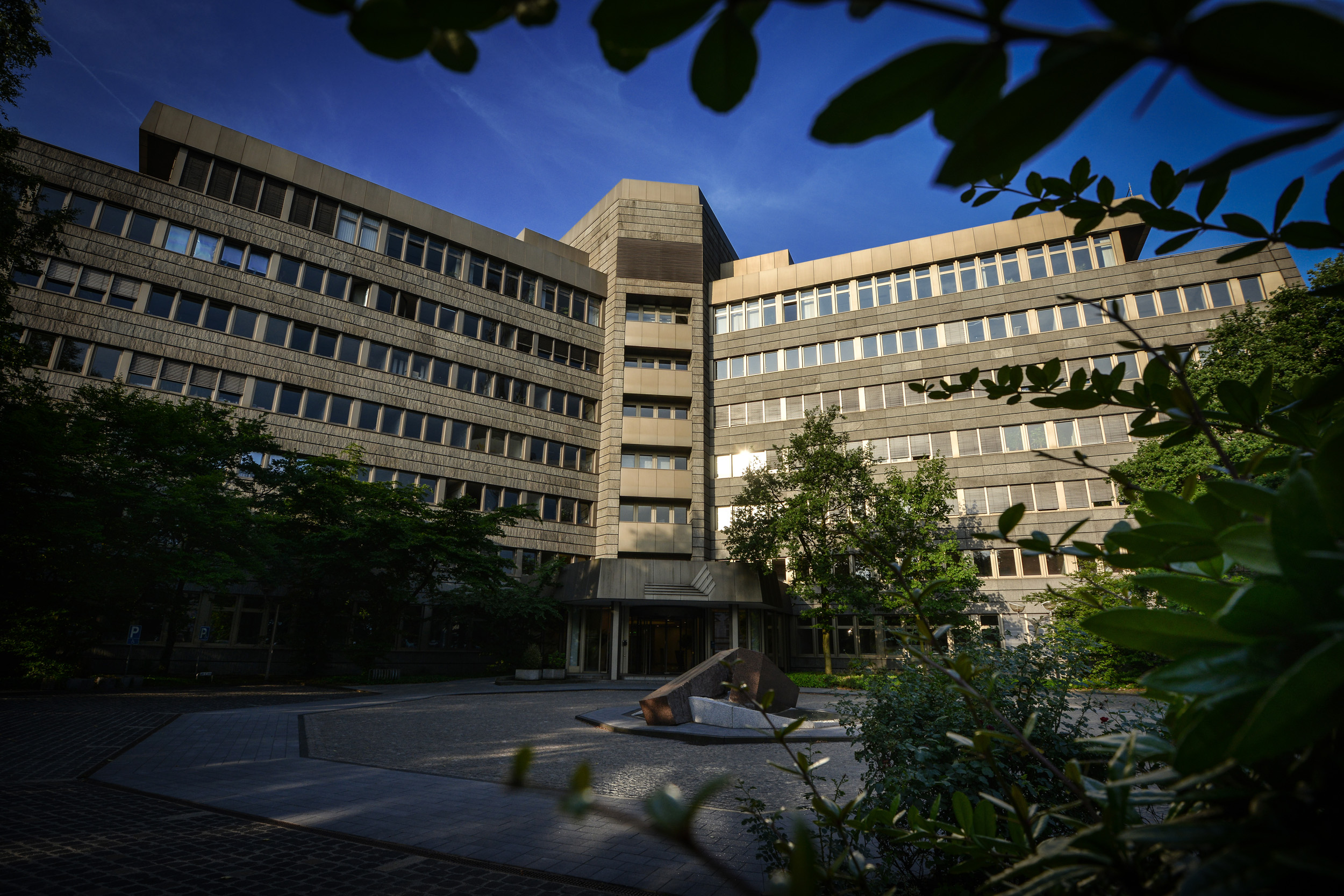 Haupteingang der DVV-Zentrale in Duisburg, umgeben von Bäumen und Sträuchern