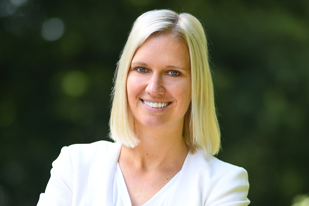 Porträt von Kathrin Naß, Pressesprecherin der DVV, vor grünem Hintergrund